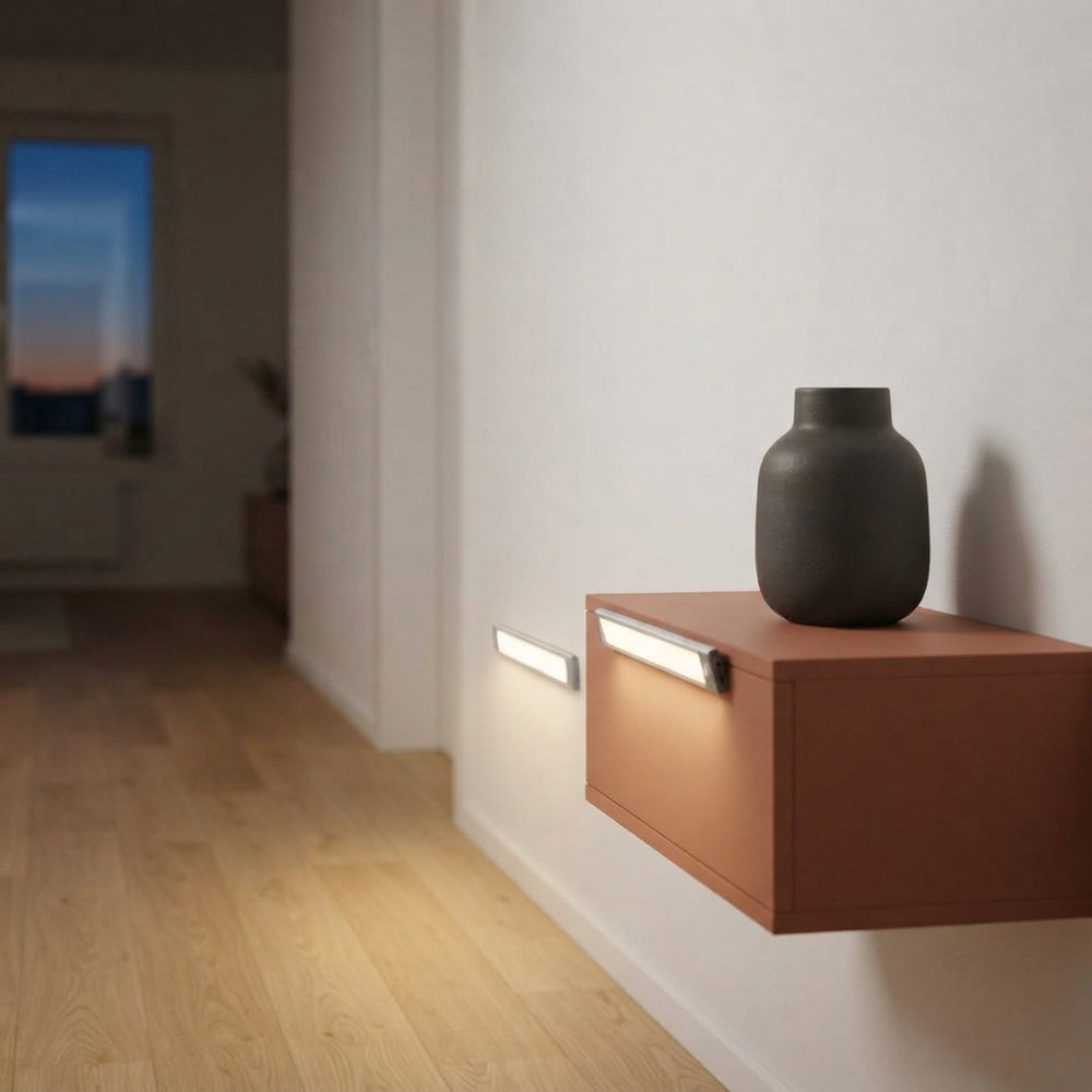 A wireless motion-sensor LED light illuminating a modern hallway with a terracotta console table and a charcoal vase.